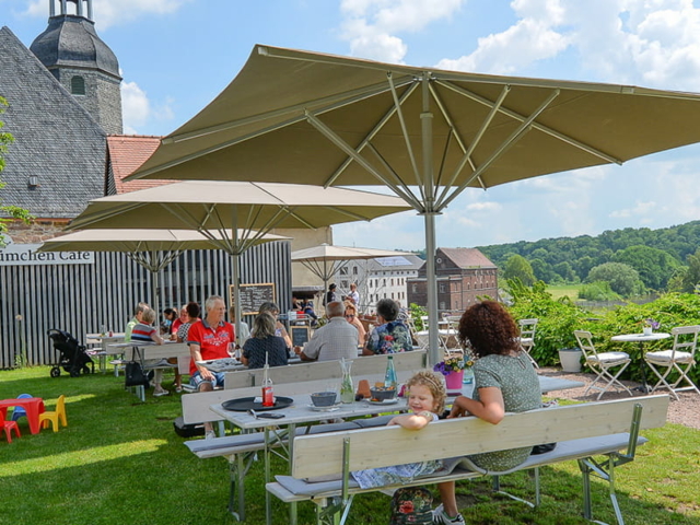 Blümchen Café Rochlitz Blick auf Terrasse mit Gästen unter Sonnenschirmen bei schönem Sommerwetter