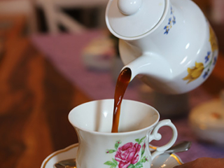 Blümchen Café Rochlitz Kaffee wird aus einer Porzellankanne mit Blümchen in eine Tasse mit floralem Muster eingegossen