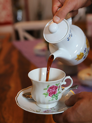 Blümchen Café Rochlitz Kaffee wird aus einer Porzellankanne mit Blümchen in eine Tasse mit floralem Muster eingegossen