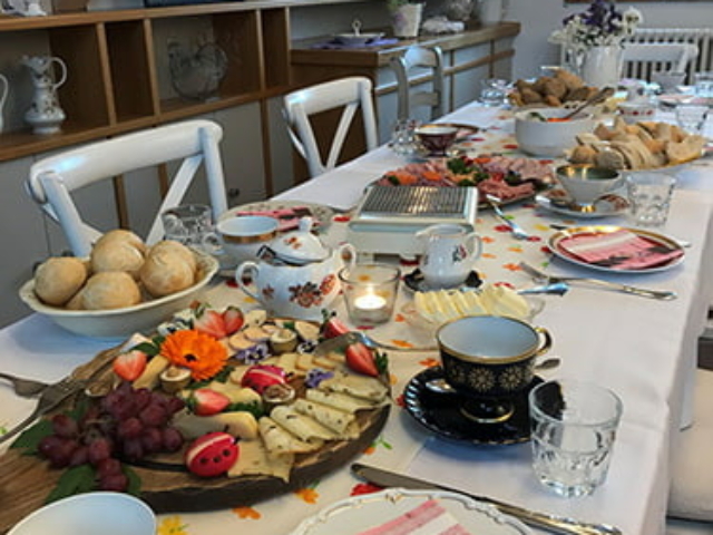 Blümchen Café Rochlitz gemütlich gedeckter Brunchtisch mit frischen Brötchen, Belag und angezündeten Kerzen