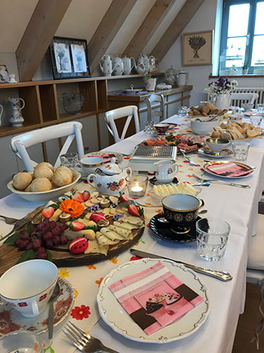 Blümchen Café Rochlitz gemütlich gedeckter Brunchtisch mit frischen Brötchen, Belag und angezündeten Kerzen