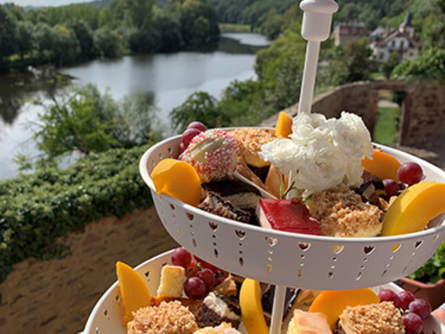 Blümchen Café Rochlitz Kuchenetagere mit vielen verschiedenen Kuchen und Zwickauer Mulde im Hintergrund