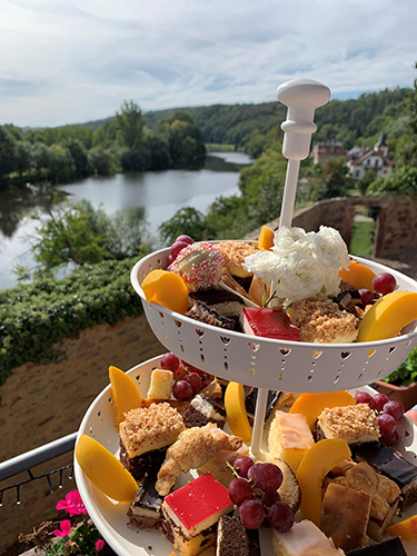 Blümchen Café Rochlitz Kuchenetagere mit vielen verschiedenen Kuchen und Zwickauer Mulde im Hintergrund