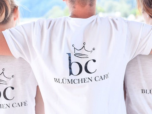 Blümchen Café Rochlitz Team mit weißen T-Shirts & Logo von hinten fotografiert mit Blick auf Zwickauer Mulde bei Sonnenschein